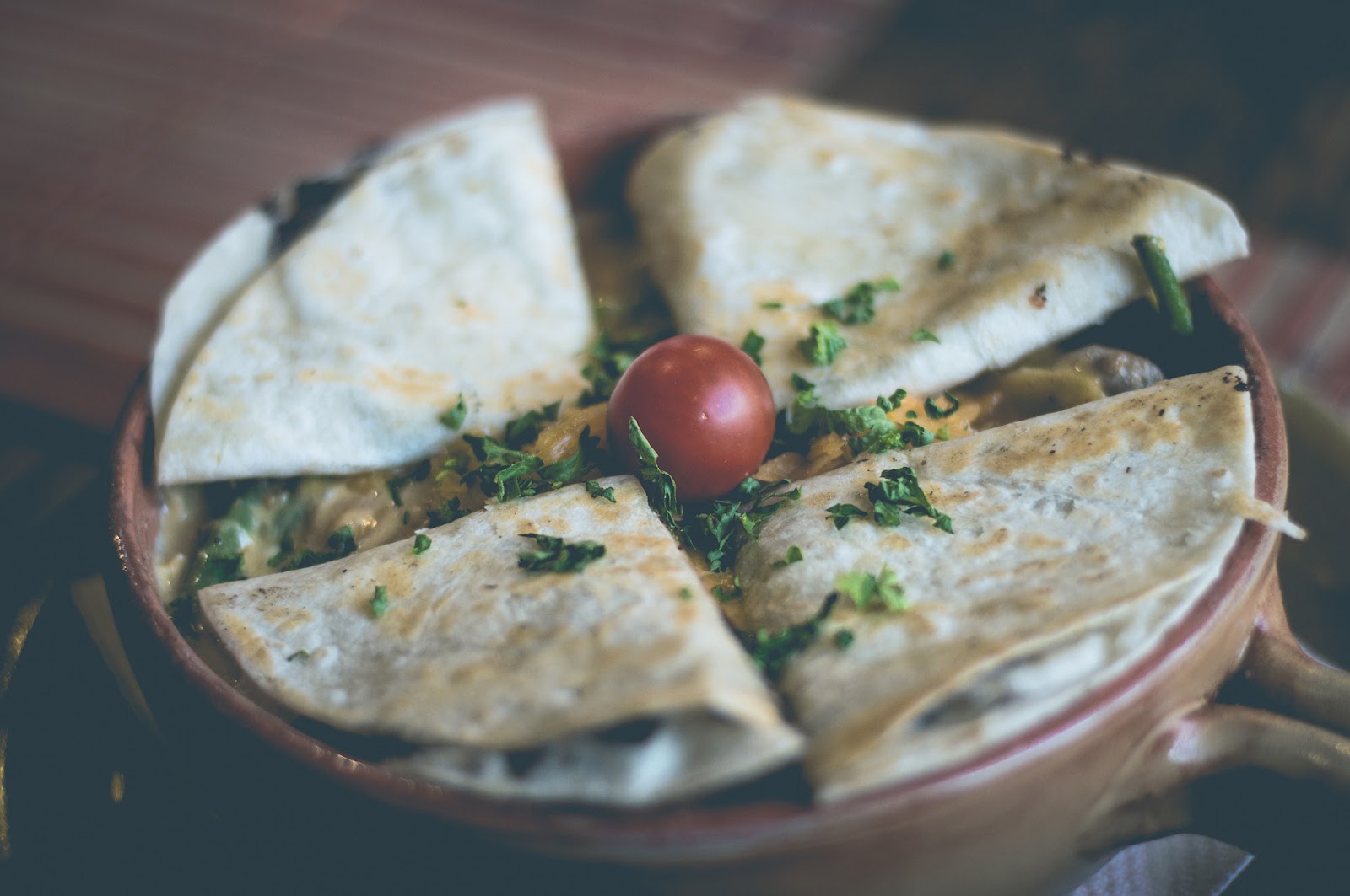 Quesadillas cut into wedges with fresh cilantro and a cherry tomato