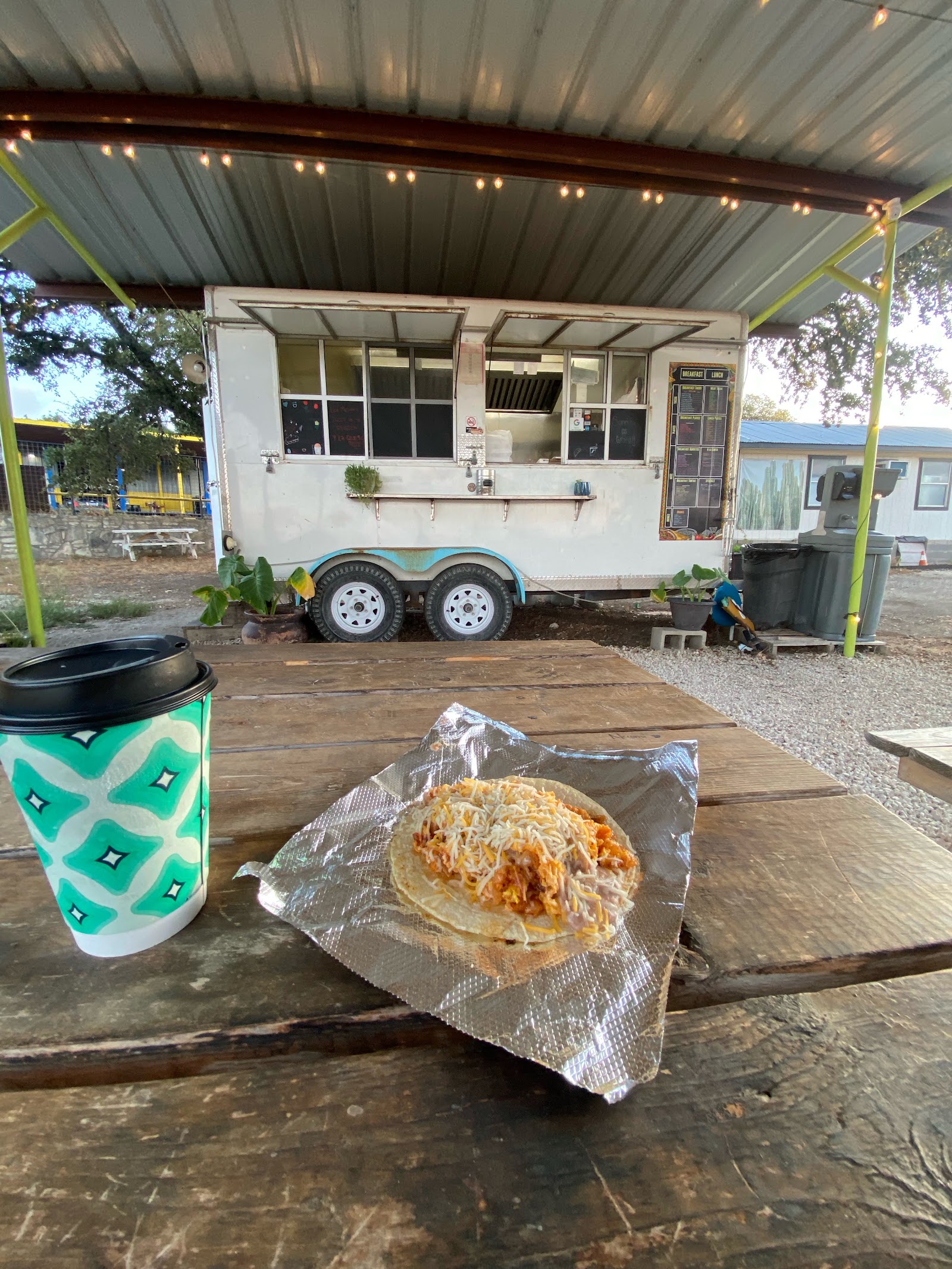 Mi Familia Taco Shop food truck exterior with a breakfast taco and coffee on the picnic table