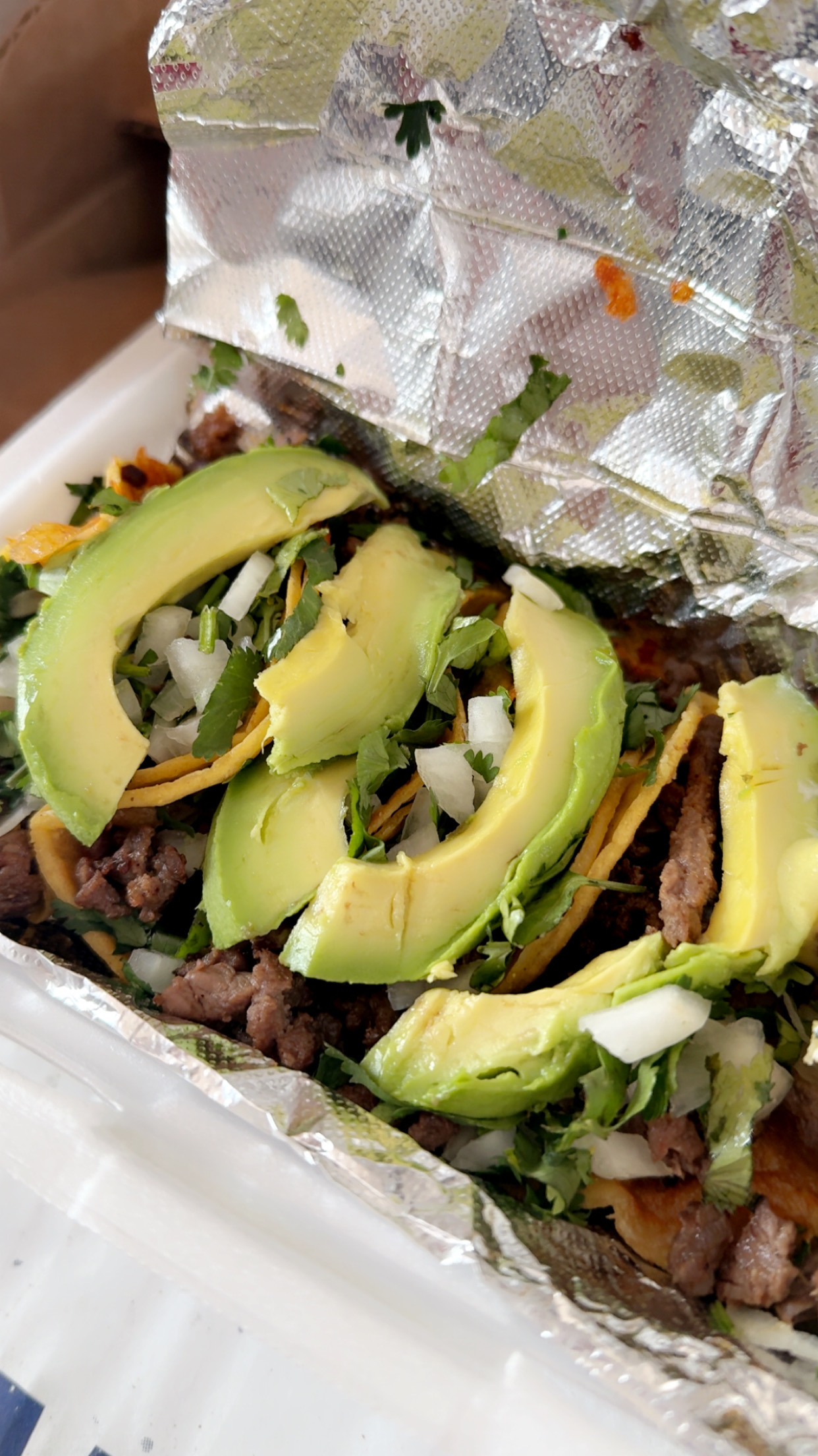 Street-style tacos topped with sliced avocado, onion, and cilantro